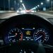 Vue réaliste du tableau de bord d’une voiture sur une autoroute de nuit, avec un voyant de dysfonctionnement moteur d’injection allumé et une ambiance cinématographique.