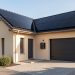 Maison individuelle française équipée de panneaux solaires noirs sur le toit et d’une batterie murale dans un garage propre éclairé par la lumière naturelle.